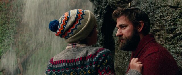 Still uit de film A Quiet Place. Lee glimlacht naar een van zijn kinderen tegen de achtergrond van een waterval